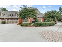 Charming brick home with a three-car garage, manicured landscaping, and a circular driveway at 2444 Ballantrae Cir, Cumming, GA 30041