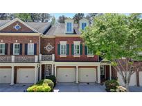 Beautiful brick townhome featuring white garage doors and well-maintained landscaping at 7512 Portbury Park Ln, Suwanee, GA 30024