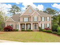 Charming two-story brick home boasts a well-manicured lawn, shutters, and welcoming front porch at 111 Glen Trl, Woodstock, GA 30188