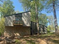 Unique, modern home with stone facade, small balcony, and large windows surrounded by mature trees at 3684 Big Springs Rd, Decatur, GA 30034