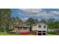 Charming brick and vinyl home featuring a two-car garage and colorful blooming azaleas at 2198 Kings Forest Se Dr, Conyers, GA 30013