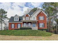 Charming two-story brick home with a covered front porch and well-manicured landscaping at 8100 Greens Mill Way, Loganville, GA 30052