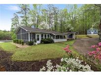 Charming home exterior with a screened porch, well-maintained lawn, and lush landscaping showcasing curb appeal at 7650 Rico Rd, Chattahoochee Hills, GA 30268