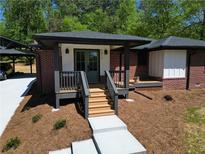 Charming brick home showcasing a cozy front entrance with stairs and manicured landscaping at 5017 Spring Hill Dr, Sugar Hill, GA 30518