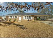 Charming brick home with a covered parking area and a well-maintained front yard at 8586 Taylor Rd, Riverdale, GA 30274