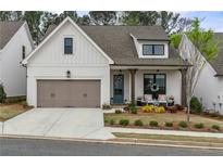 Charming cottage-style home with a two-car garage, covered porch, and well-maintained landscaping at 228 Idylwilde Way, Canton, GA 30115