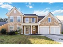 Two-story home with a stone and siding exterior, two-car garage and a well-manicured front lawn at 2319 White Alder Dr, Buford, GA 30519