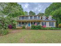 Charming two-story home with a welcoming front porch, American flag and landscaped yard at 293 Country Lake Dr, Mcdonough, GA 30252