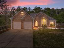 Charming brick home boasts a manicured lawn, two-car garage, and lush landscaping under a vibrant sunset sky at 3229 Summer Stream Nw Ln, Kennesaw, GA 30152