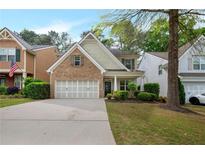 Charming two-story home boasts a brick facade and a well-manicured front yard with lush landscaping at 272 Ascott Ln, Woodstock, GA 30189