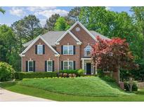 Charming two-story brick home featuring manicured landscaping, a symmetrical facade, and a welcoming front entrance at 7020 Weybridge Dr, Cumming, GA 30040
