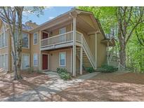Exterior view of tan condominium with red doors, walkways, and lush green trees at 907 Country Park Se Dr, Smyrna, GA 30080