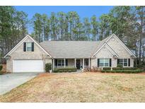 Charming single-story brick home with a well-manicured lawn, covered porch and attached two car garage at 1935 Knight Cir, Loganville, GA 30052