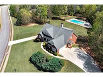 Stunning aerial view of a brick home with a spacious yard and in-ground pool in a lush, green neighborhood at 7804 Gusty Trl, Douglasville, GA 30135