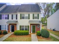 Charming townhome with manicured bushes, neutral siding, green shutters and door, and brick accents at 2758 Snapfinger Mnr, Decatur, GA 30035