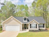 Charming single-story home features a manicured lawn, attached garage, and inviting front entrance at 135 Kimbell Farm Dr, Locust Grove, GA 30248