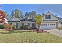 Charming single-Gathering home featuring a manicured front lawn, brick accents, and an attached two-car garage at 1112 Autumn Glen Way, Dacula, GA 30019