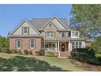 Stunning brick two-story home featuring manicured lawn, lush landscaping, and a welcoming front porch at 403 Grassmeade Way, Snellville, GA 30078