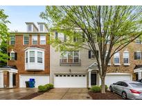 Charming townhome featuring brick and gray painted facade, complemented by an attached two-car garage and tasteful landscaping at 11302 Musette Cir, Alpharetta, GA 30009