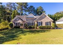 Charming brick home with a well-manicured lawn, complemented by mature trees and manicured shrubs at 5494 White Cedar Ter, Sugar Hill, GA 30518