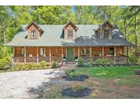 Charming log cabin home with inviting front porch, landscaped yard, and a green roof at 135 Fiddle Crk, Social Circle, GA 30025