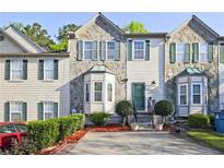 Charming townhome featuring stone accents, a well-manicured lawn, and a private driveway at 2557 Summit Cove Dr # 128, Duluth, GA 30097