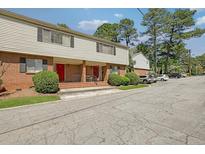 Brick and vinyl sided townhome with a red door and well manicured shrubs at 3312 Northcrest Rd # C, Atlanta, GA 30340