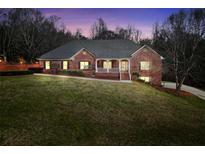 Charming brick home featuring a manicured lawn, covered porch, and inviting curb appeal at twilight at 503 Clearwater Dr, Mcdonough, GA 30252