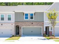 Charming townhome with brick accents, a gray garage door, and manicured landscaping at 1616 Ruskin Way, Marietta, GA 30062