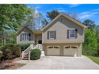 Inviting two-story home with a well-maintained front yard and two-car garage and mature trees on a sunny day at 501 Woodland Trce, Woodstock, GA 30189