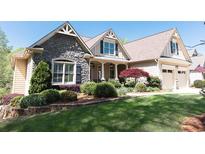 Charming home featuring a stone facade, manicured lawn, and inviting front porch at 5095 Hamby Hollow Ln, Cumming, GA 30028