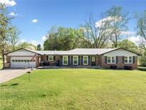 Ranch home featuring a lush green lawn and inviting curb appeal with a charming brick exterior and an attached garage at 630 Cambridge Dr, Marietta, GA 30066