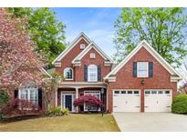 Charming two-story brick home featuring a manicured lawn, mature landscaping, and a two-car garage at 1442 Valley Glen Way, Dunwoody, GA 30338