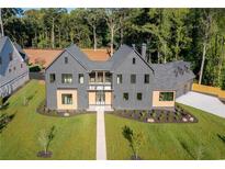 Stunning gray modern home with a manicured lawn, complemented by lush trees in the background at 115 Nova Ln, Roswell, GA 30075