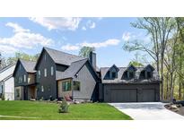 Stunning modern farmhouse-style home featuring a three-car garage, dark siding, and meticulous landscaping at 115 Nova Ln, Roswell, GA 30075