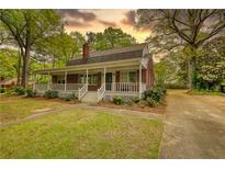 Charming brick home featuring a welcoming front porch, a well-manicured lawn, and an inviting facade at 177 Fairview Dr, Fairburn, GA 30213