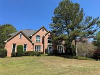 Beautiful two-story brick home with mature landscaping and a well-manicured lawn at 680 Estate Club Cir, Roswell, GA 30075