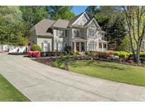 Charming two-story home with manicured landscaping, a well-kept lawn and a long driveway leading up to the house at 1420 Lockridge Dr, Cumming, GA 30041