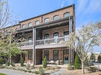 Inviting brick townhouse with covered balconies and well-manicured landscaping, perfect for relaxed outdoor living at 6380 Cortland Walk, Alpharetta, GA 30005