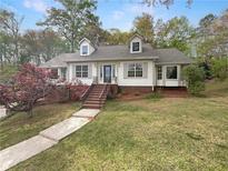 Charming home with manicured lawn, blooming tree, and inviting staircase leading to the front door at 8608 Creekview Ct, Douglasville, GA 30135