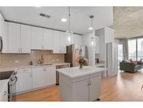 Bright kitchen features white cabinets, stainless appliances, an island, and views of the living area at 860 Peachtree Ne St # 1103, Atlanta, GA 30308