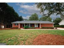 Charming single-story red brick home featuring a well-manicured lawn and mature landscaping at 2533 Whispering Pines Dr, Grayson, GA 30017
