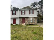 Two-story townhome with stone facade and red doors, nestled in a residential neighborhood at 3604 Hopkins Ct, Powder Springs, GA 30127
