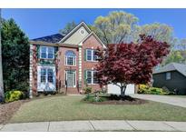 Charming two-story brick home with a well-manicured lawn and mature landscaping at 320 Hillside Manor Dr, Sugar Hill, GA 30518