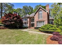 Charming brick home with manicured lawn, mature trees, and beautiful landscaping at 1418 Waterford Green Dr, Marietta, GA 30068