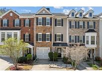 Charming townhome exterior featuring a mix of brick and stone facade, well-maintained landscaping, and attached garages at 3972 Church View Ln, Suwanee, GA 30024