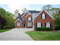 Traditional brick home with manicured lawn, dark shutters, and a large driveway, offering classic curb appeal at 2165 Sugarstone Ct, Lawrenceville, GA 30043