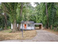 Charming single-story home with covered parking and a welcoming orange front door nestled among mature trees at 2437 Clarissa Nw Dr, Atlanta, GA 30318
