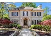Elegant two-story home featuring a manicured front yard and a stone walkway leading to the arched front door at 9860 Hunt Club Way, Johns Creek, GA 30022