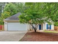 Charming single-story home features a two-car garage, manicured lawn, and inviting entrance with a blue door and blue shutters at 209 Southerness Ct, Stockbridge, GA 30281